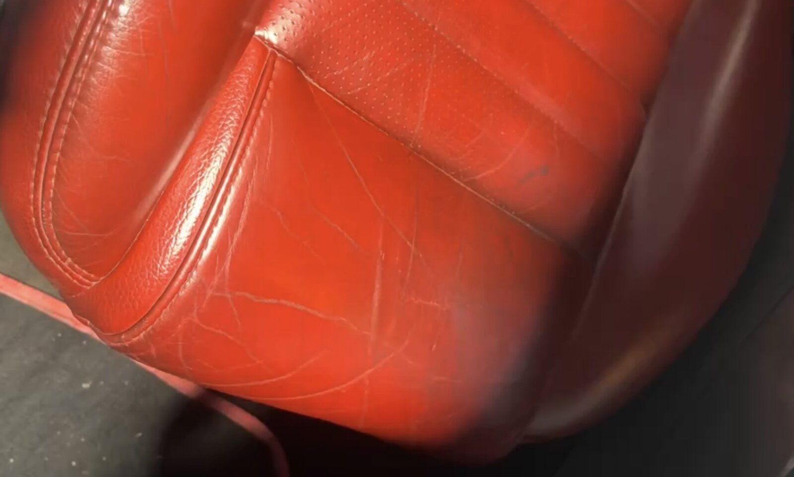Cracked and worn red leather car seat bolster before restoration by PJ Leather Paint