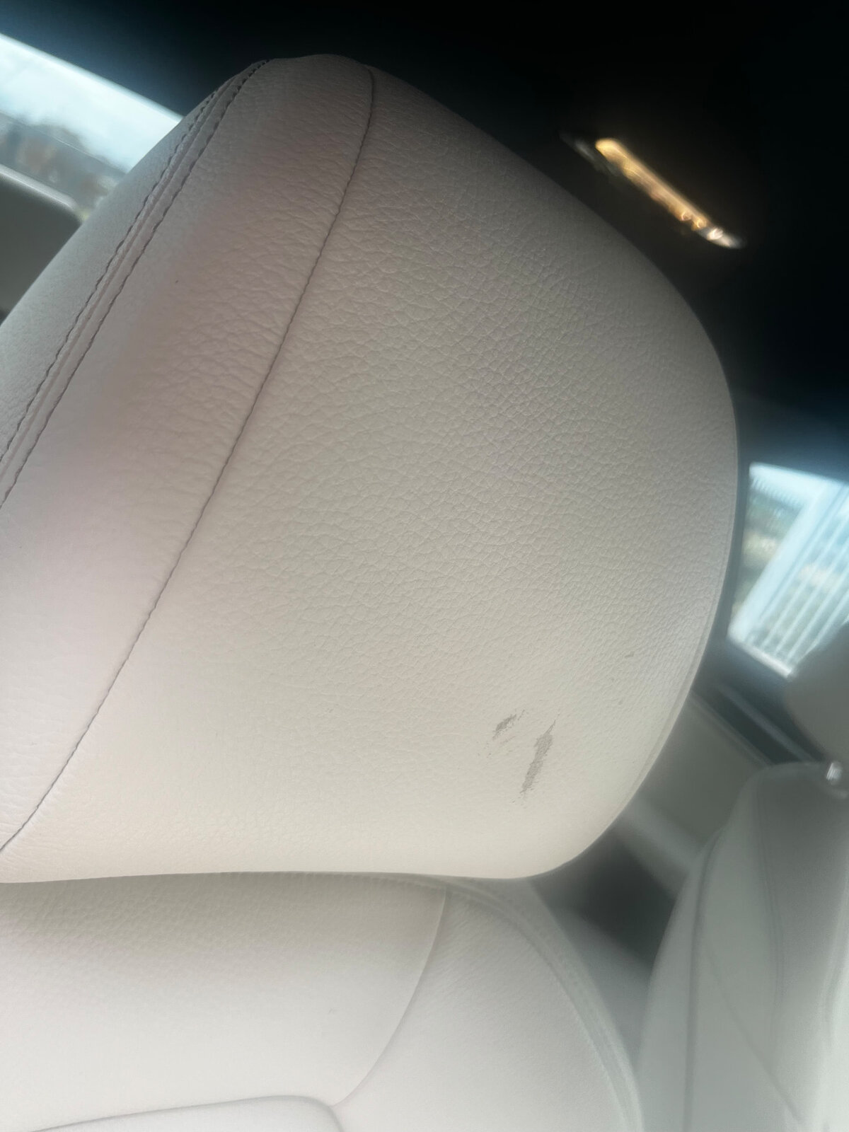 Scuffed off-white leather car headrest before repair by PJ Leather Paint
