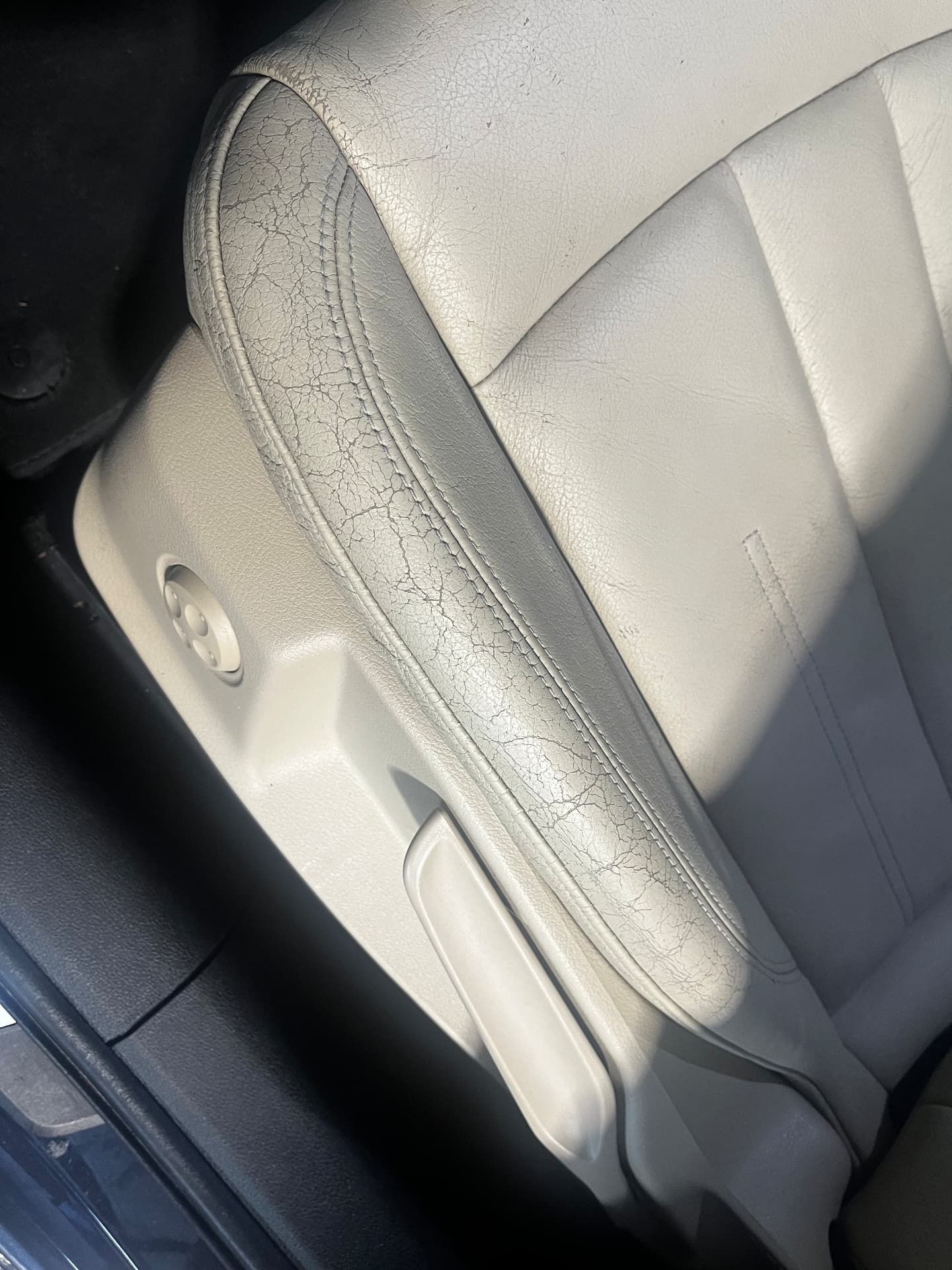 Cracked light leather car seat bolster before repair by PJ Leather Paint