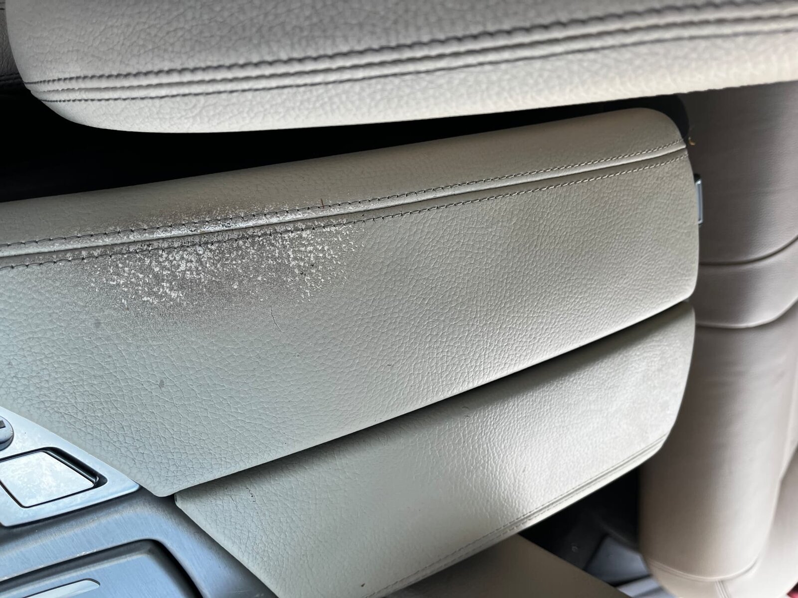 Scuffed beige leather BMW centre console armrest before repair by PJ Leather Paint