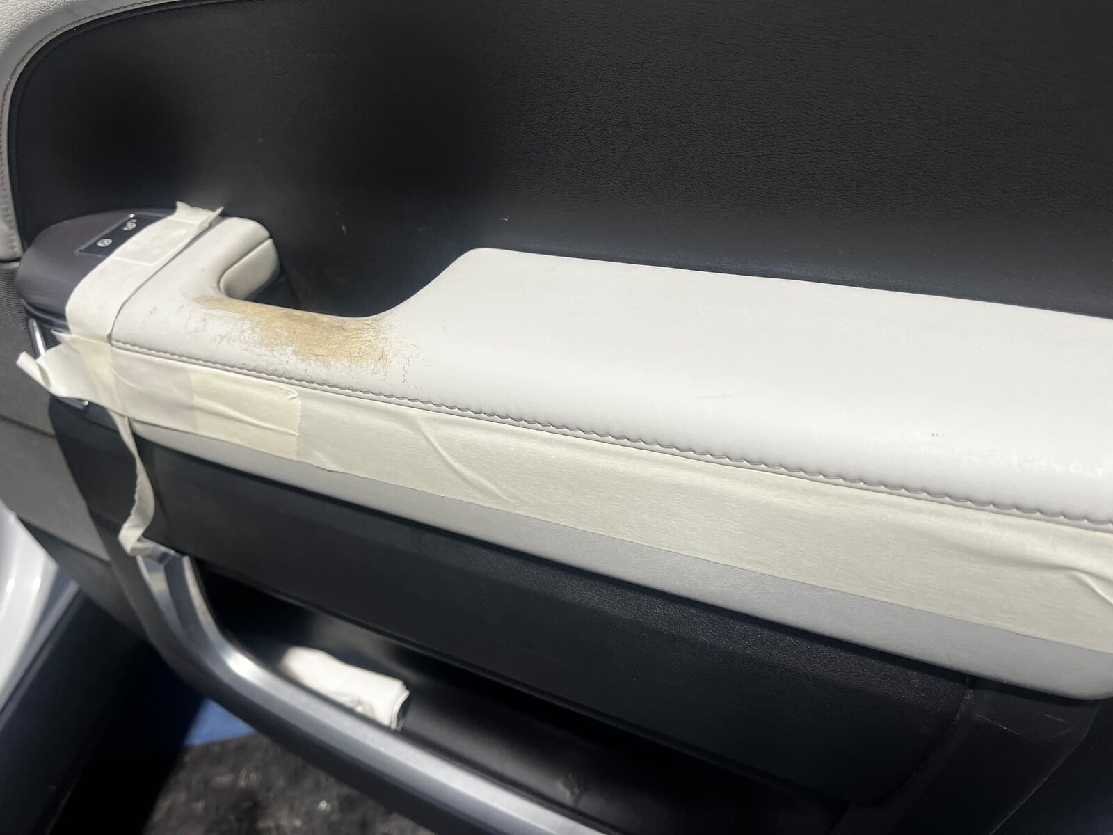 Worn light grey leather Land Rover Defender door panel armrest before repair by PJ Leather Paint