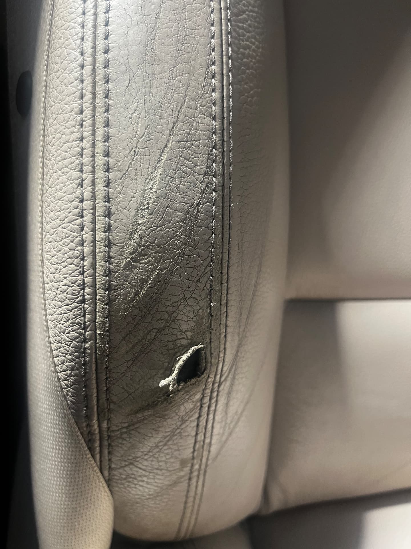 Torn and cracked light leather seat bolster before repair by PJ Leather Paint